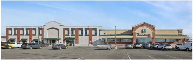 Modern commercial building with brick and stone exterior in a parking lot with several parked vehicles
